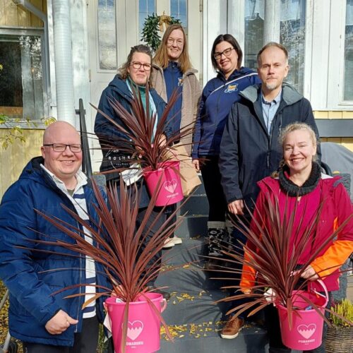 Asumiskokeilijat, Pomarkun kunnanjohtaja ja Palvelusihteeri-kirjastovirkailija, sekä hanketyöntekijät yhteiskuvassa Villa Rouheen ulkorappusilla. Käsissä asumiskokeilijoilla lahjaksi saadut pinkit ämpärit joissa pinkit kukat.