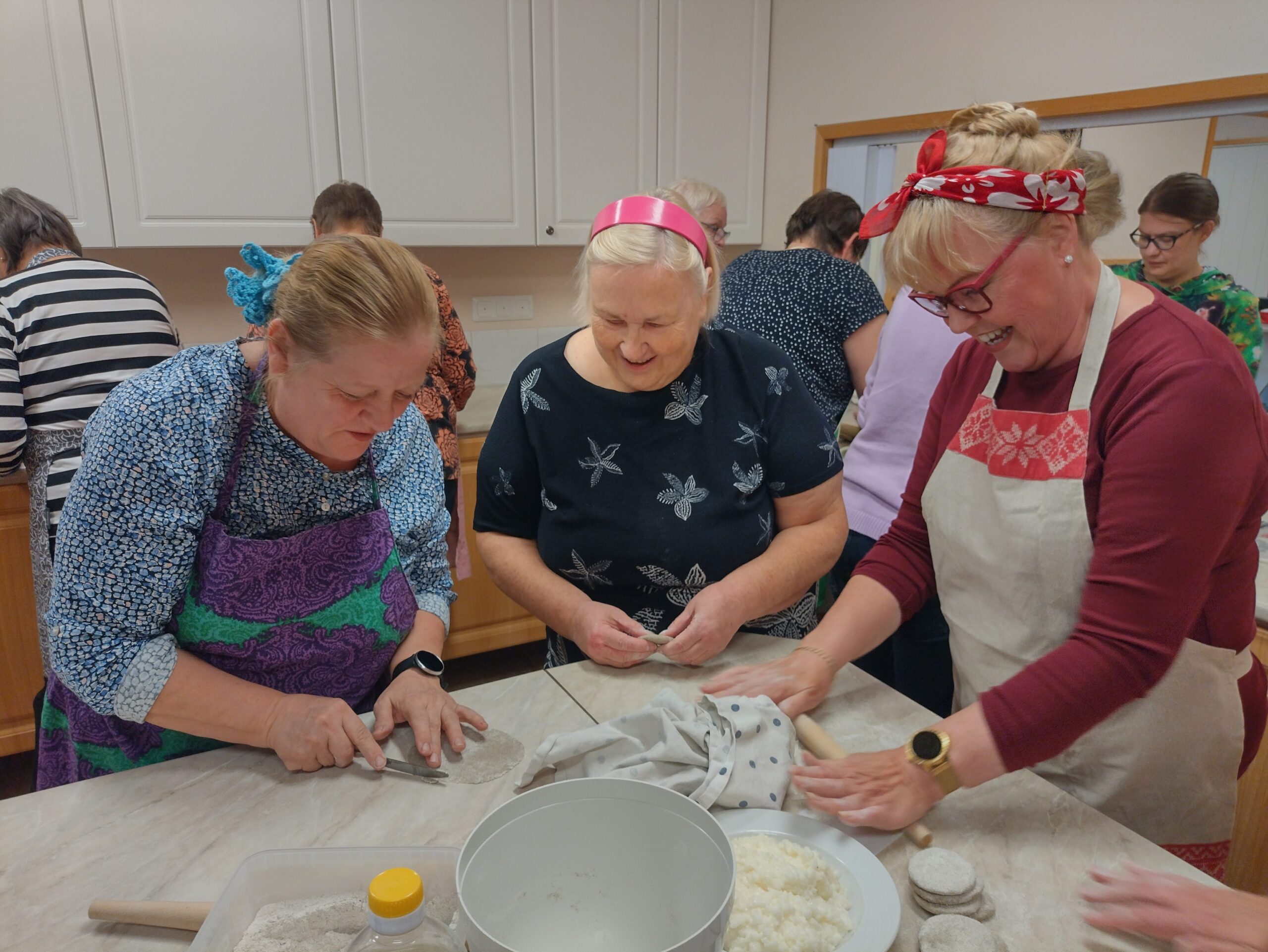 Naiset leipovat karjalanpiirakoita.