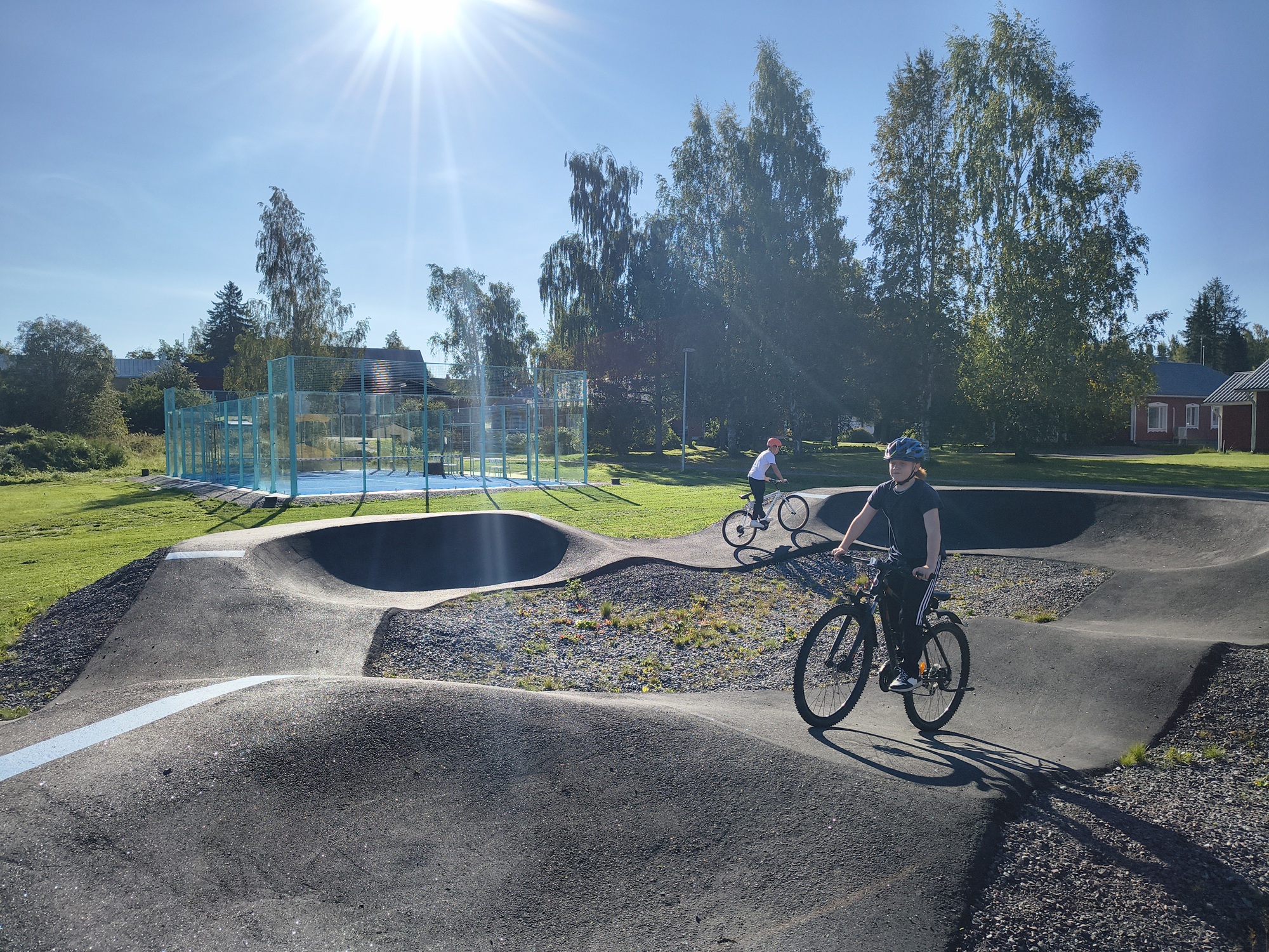 Kaksi alakouluikäistä ajaa polkupyörillä Pumptrack radalla.